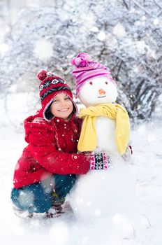 Girl makes a snowman outside in winter time