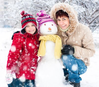 Happy mother and daughter with snowman winter portrait