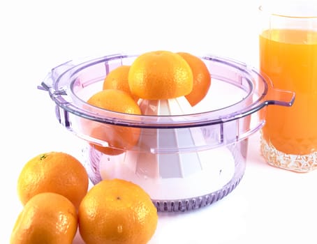 Ripe tangerines in a juicer and a glass of juice