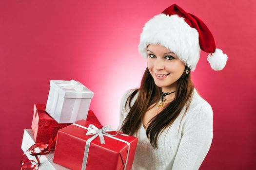Photo of a beautiful young brunette female wearing a santa hat and holding  wrapped christmas gifts.