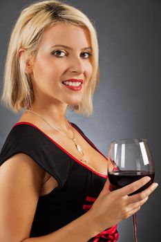 Photo of a beautiful blond female holding a glass of red wine.
