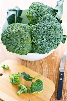 Fresh uncooked broccoli in colander and chopping board