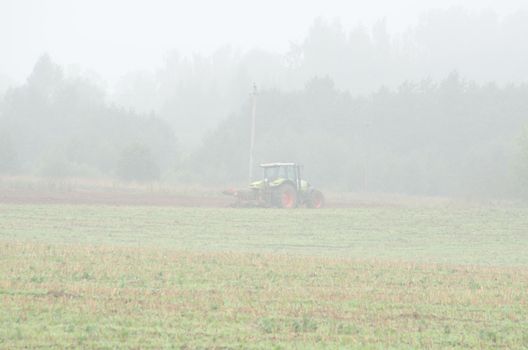 agriculture tractor equipment plow field in early morning fog.