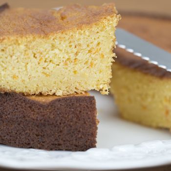 A cut homemade cake showing its texture on a wooden surface.