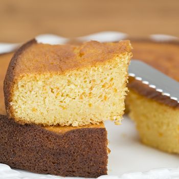 A cut homemade cake showing its texture on a wooden surface.