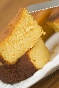 A cut homemade cake showing its texture on a wooden surface.