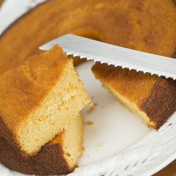 A cut homemade cake showing its texture on a wooden surface.