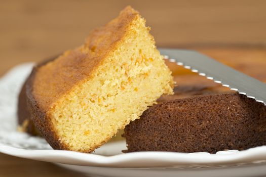 A cut homemade cake showing its texture on a wooden surface.