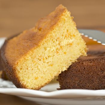 A cut homemade cake showing its texture on a wooden surface.