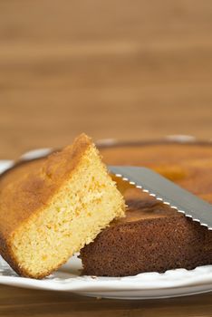 A cut homemade cake showing its texture on a wooden surface.