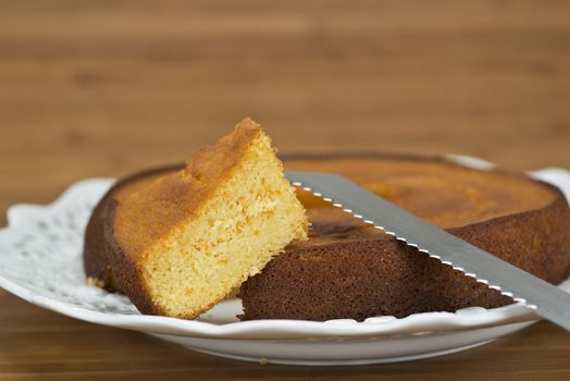 A cut homemade cake showing its texture on a wooden surface.