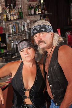 Attractive middle aged biker couple with bandannas in bar