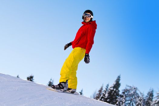 Snowboarder sliding down a slope on a sunny day