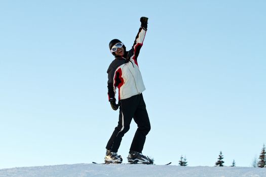 portrait of skiers throwing up her hands on the slopes in a sunny day