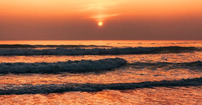 Beautiful colorful sunset over the ocean's waves.