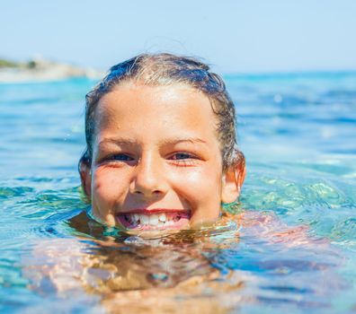 Closeup portrait of young girl swimming in the transparent sea