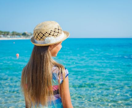 Back view of cute girl in hat on the beach