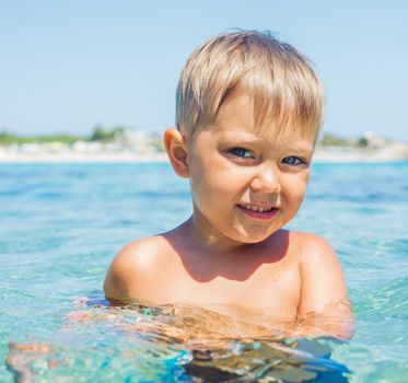 Portrait of young boy swimming in the transparent sea