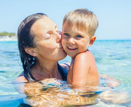 Portrait of young boy swimming with his mother in the transparent sea