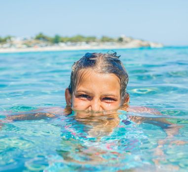Closeup portrait of young girl swimming in the transparent sea