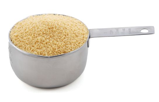 Cous cous presented in an American metal cup measure, isolated on a white background