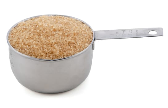 Demerara sugar presented in an American metal cup measure, isolated on a white background