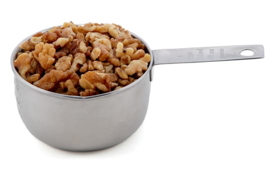 Chopped walnuts presented in an American metal cup measure, isolated on a white background