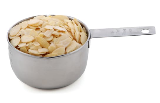 Flaked almonds presented in an American metal cup measure, isolated on a white background