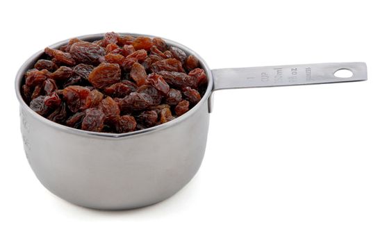 Raisins presented in an American metal cup measure, isolated on a white background