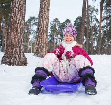 Cute girl on sleds in snow forest.