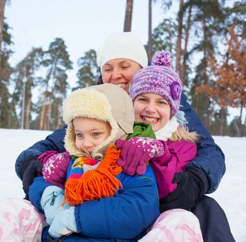 Mother with her two kids is sledging in winter-landscape. Focus on the boy.