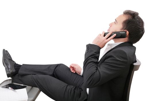young business man relaxing at office desk and talking on mobile phone, isolated on white