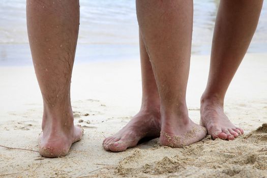 Legs of couple on the sand beach