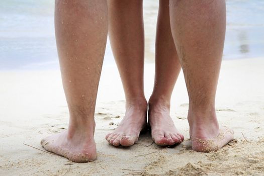 Legs of couple on the sand beach