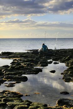 The fisherman at coast of ocean on a sunset. Mauritius