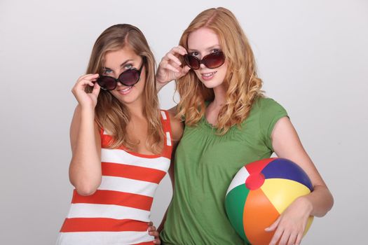 Two young woman with summer shades and a beach ball