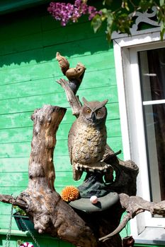 Wooden owl and squirrel in front of a cottage
