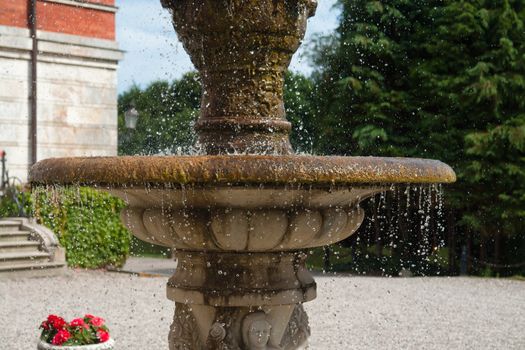 The gush of clear water splashes in a tradional European ornated stone fountain