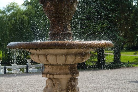 The gush of clear water splashes in a tradional European ornated stone fountain