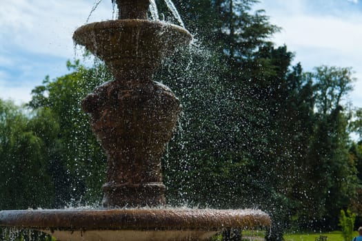 The gush of clear water splashes in a tradional European ornated stone fountain