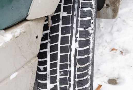 closeup of car tire tread protector full of snow in winter.