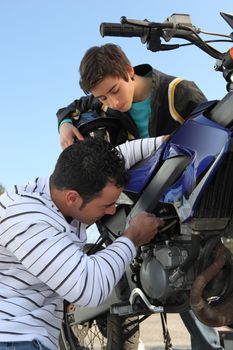 Father and son repairing their motorcycle