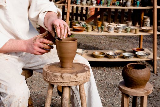 Potter in white clothes making a pot
