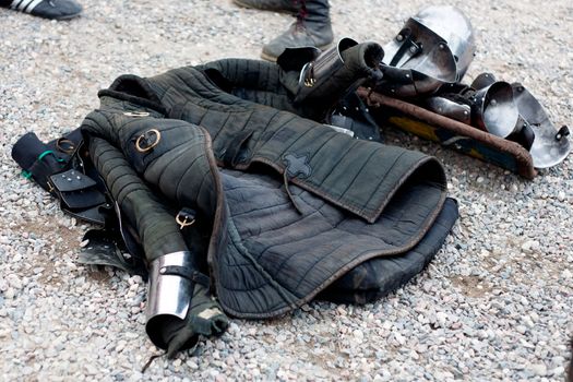 Several parts of replica of medieval europian armor on gravel
