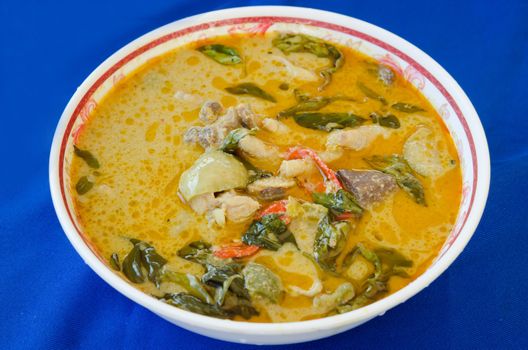 green chicken curry in bowl on blue background 