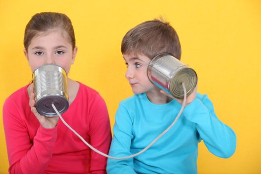 Brother and sister speaking through tin can and string