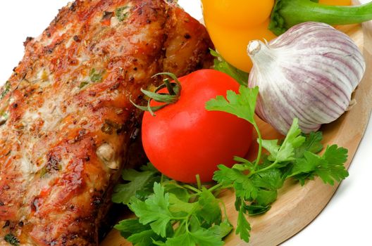 Arrangement of Delicious Roasted Pork and Vegetables with Parsley, Tomato , Garlic and Bell Pepper closeup on Cutting Board