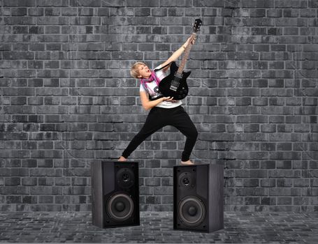 girl with guitar and speakers on brick background