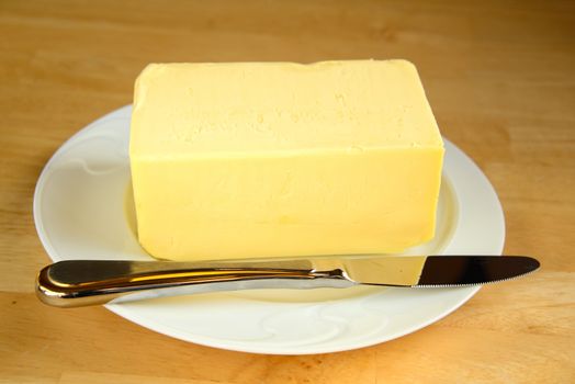 Halv a kilogram of butter on a white plate with a knife