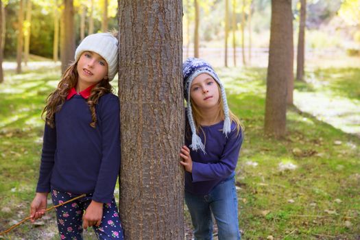 Autumn sister kid girls playing in poplar tree forest near trunk in nature outdoor